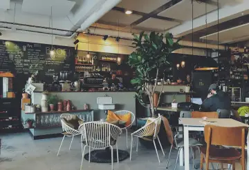 Café-Innenraum mit Pflanzen und Holztischen